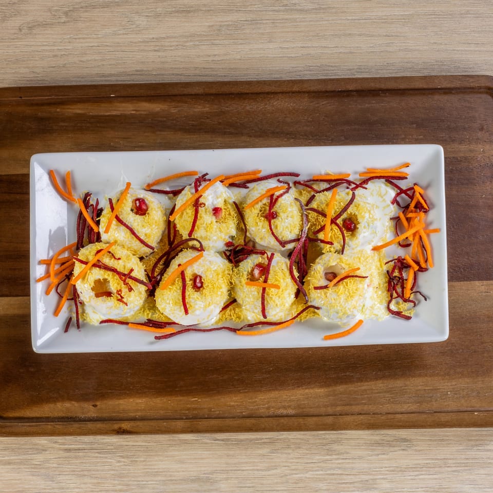 Honest Indianapolis's Indian dish features white, donut-shaped items topped with yellow sprinkles, red strips, and orange strips.